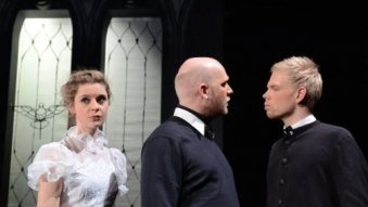 Eine Sängerin im weißen Kleid, zwei Männer im schwarzen Hemd