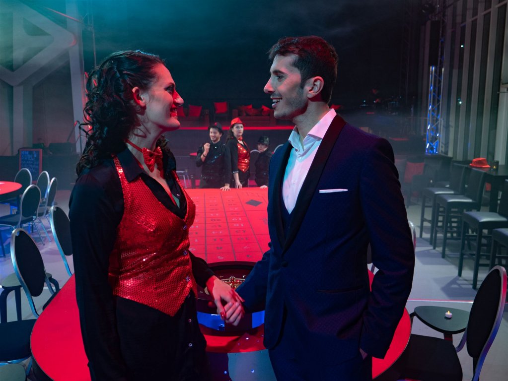 Violetta und Alfredo, im Hintergrund beobachten sie Flora und Croupier 